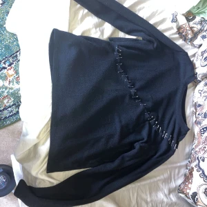 Svart långärmad tröja med säkerhetsnålar design  - Säkerhetsnål designen har jag gjort själv. Tröjan vill jag sälja den eftersom jag helt enkelt inte klär mig i den stilen längre, det är altså inget fel på självaste tröjan. Tröjan har ett tjockt och varmt material 