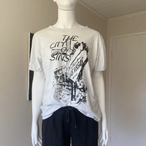 Vit tshirt - T-shirten har egen design på trycket. Den är oanvänd. Plaggets mått i cm: B 44, L 62.