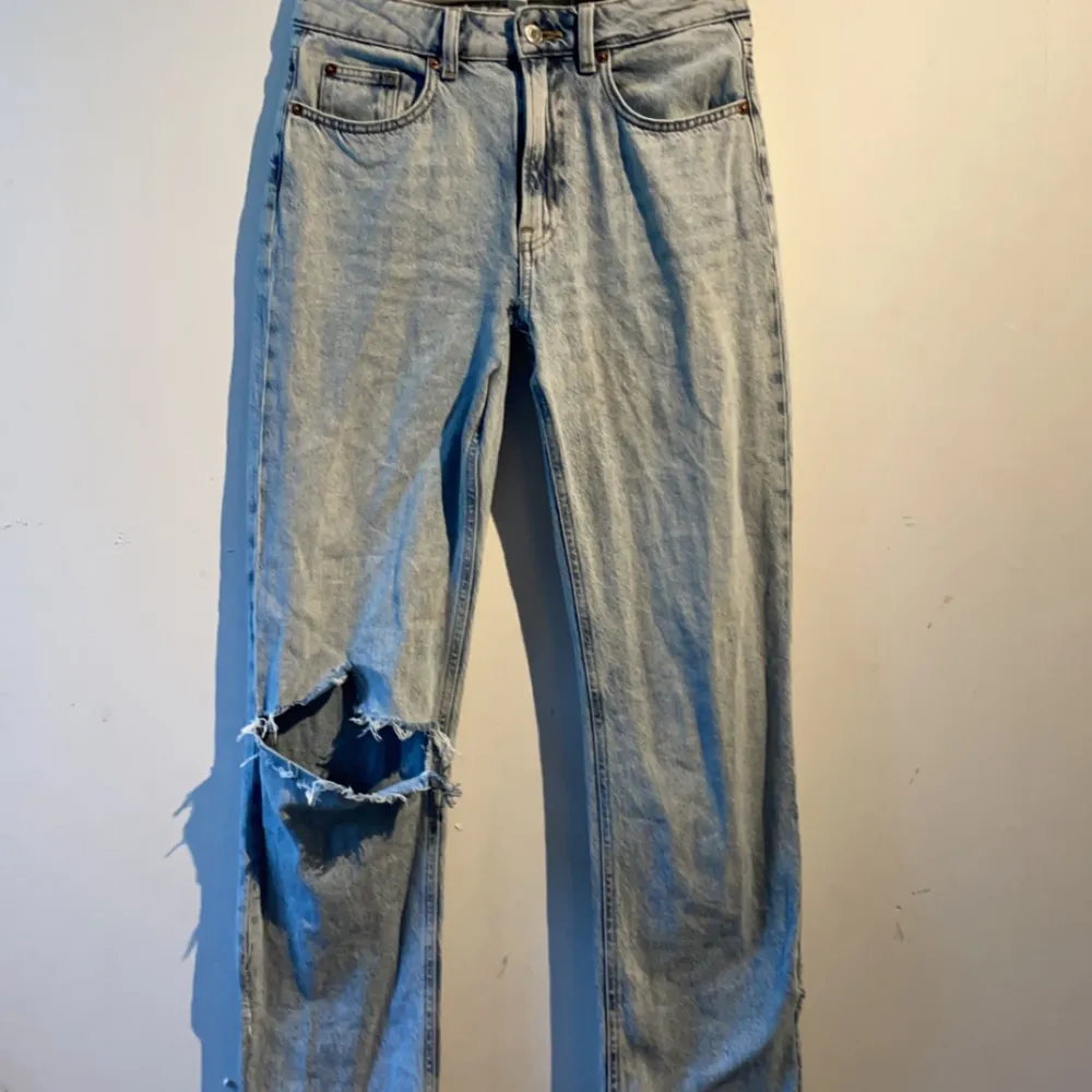 Blåa jeans som är lågmidjade, detaljer på fickan bak och nere vid benen, 1 hål i knäet. Jeans & Byxor.