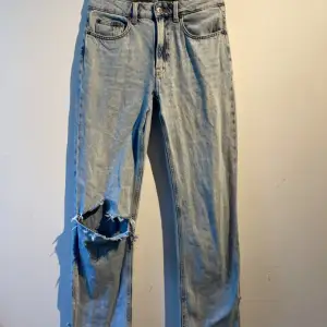 Blåa jeans som är lågmidjade, detaljer på fickan bak och nere vid benen, 1 hål i knäet