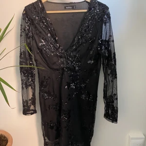 Klänning med glitter - Vacker svart klänning med glittriga detaljer. Sitter tight och går till mitten på låten på mig som är 172 och vanligtvis har S/M. Har sytt ihop vid bysten men det går att sprätta upp enkelt.