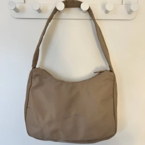 Liten väska🤎 - Säljer en brun-beige väska som är köpt på GinaTricot. Det finns två supersmå fläckar som knappt syns. Väskan har ett innefack med dragkedja❤️ Skriv för fler bilder eller info❤️