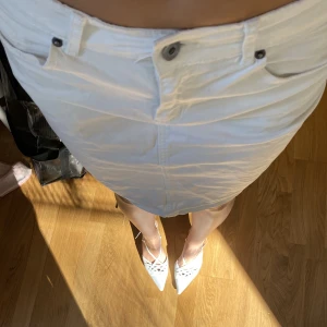 Kort midjad jeans kjol - Vit jeanskjol med kort midja och fina detaljer på bakfickor. 