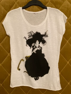 T-shirt från H&m  - Vit T-shirt med motiv från H&m. 100% bomull, strl S, använd endast en gång i gott skick! Köparen står för frakt 