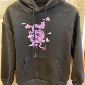Svart hoodie med kinesisk drake - Svart hoodie med lila/rosa kinesisk drake på🖤🐉 Är lite sliten med tanke på att det var min favvo hoodie men den är fortfarande väldigt bekväm😊