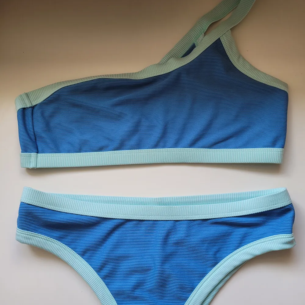 Blå asymmetrisk bikini i gott skick köpt i USA. Toppen är inte vadderad. Tyget är elastiskt och sitter skönt och bra.. Övrigt.