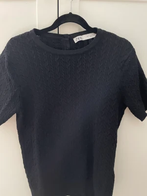 Svart zara tröja - En fin tjockare zara t-shirt med flätad kontur. Med fina pärl knappar baktill.