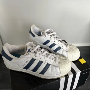 Adidas superstar sneakers marinblå och beige - Sneakers från Adidas superstar med marinblå stripes och beige tå. Gott skick. 