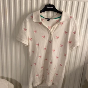 Tröja med tennis raket på  - Det är en piké tröja med rosa tennisrack på den har aldrig kommit till användning och det är detför jag säljer den