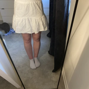 Vit fin kjol  - Kjolen är vit med en tajt resor i midjan. Nedan är den lite ribbad med ”volanger”. 50 kr + frakt