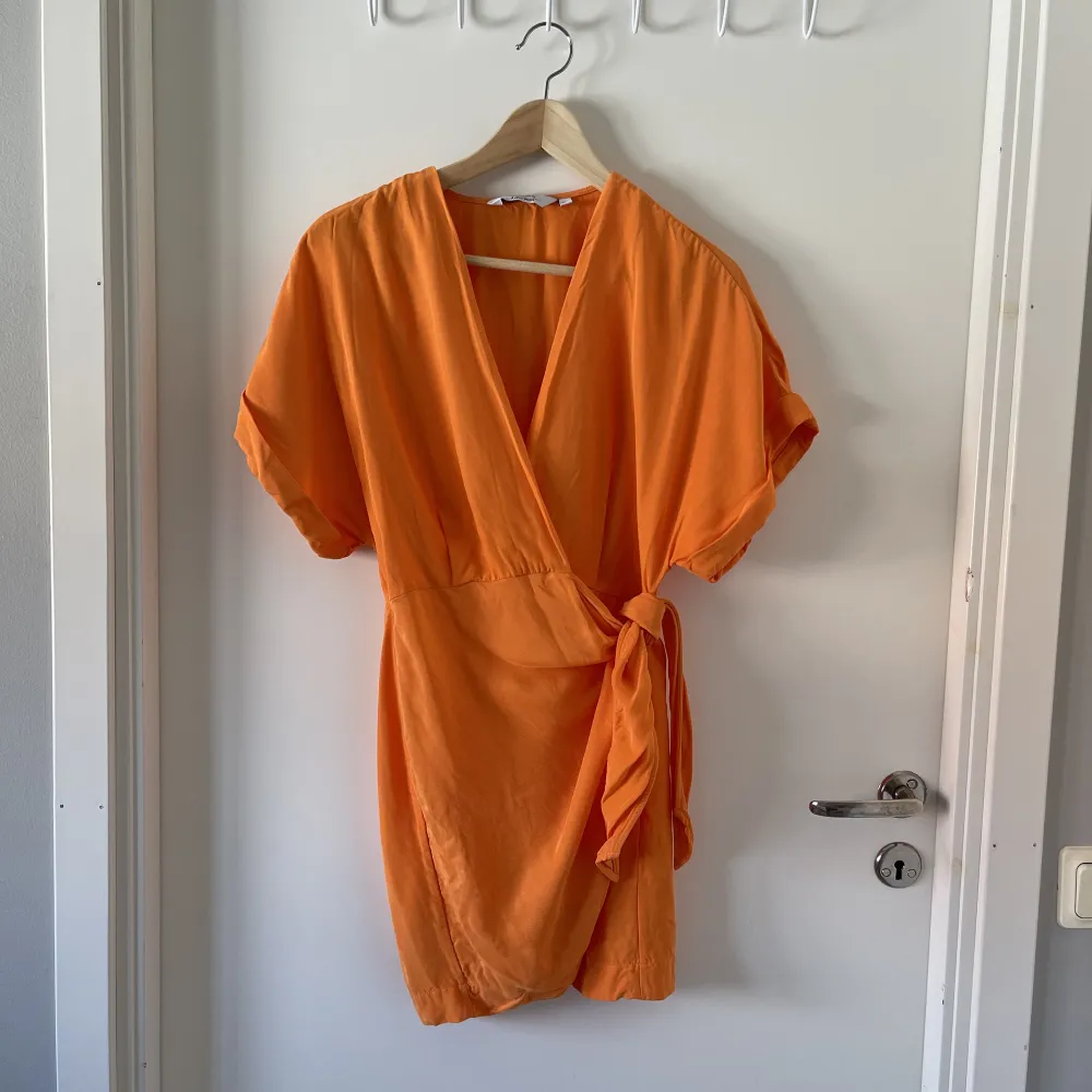 Säljer en jättefin orange omlottklänning från & other stories. Storlek 36. Jätte fint skick! Väldigt kort, jag är 165cm och den går strax nedanför rumpan på mig.. Klänningar.