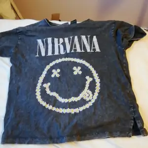En tunn t-shirt med nirvana på. Passar utmärkt till sommaren. Den är en mörkare grå färg. Inte så väl använd. 