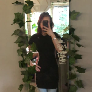 Klänning  - En svart tajt klänning med röd och vit rand på sidan💕