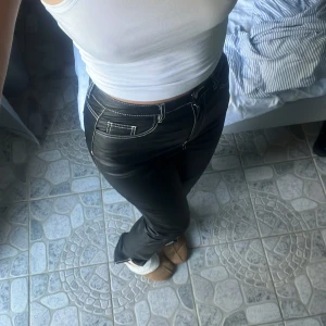 Byxor - Svarta byxor med vita sömmar och slits nedtill. Svåra att göra tillrätta på bild. Skulle säga midrise, ksk något högre. Strlk 36 men passar även 38. Innerben 84 cm. Midja 38 midjemått tvärs över. Lapp kvar. Från missguided tall