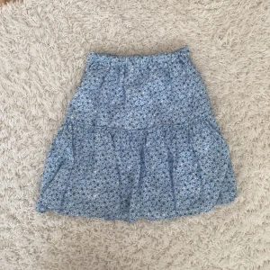 Blå kortkjol - En mycket fin mönstrad kjol som passar perfekt till våren och sommaren med dess fina färg. Säljs pågrund av för liten storlek. Kjolen är ifrån en kollektion, NA-KD x Pamela. Frakten ingår i priset🦋