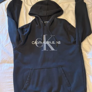 Calvin Klein Jeans Hoodie - Svart Calvin Klein Jeans hoodie i storlek M. Passar bra på mig som är 185. Pris kan diskuteras. Inte så väl använd utan den har mest stannat i garderoben ett bra tag.
