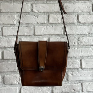 Brun läder väska  - Brun läder axelremsväska, inga skador och har fortfarande sin glans. Mått 20cm x 20 cm.