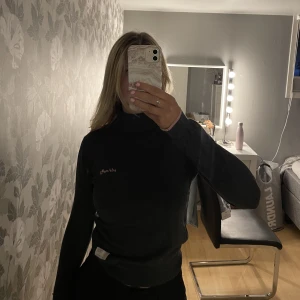 Odd Molly tröja - Odd Molly tröja med hög krage som går att vika ner. Den har rosa små rosetter längst ner på vardera ärm💗