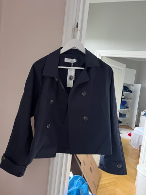 Kort kappa  - Jättefin kort trenchcoat från ByIC. Storlek M, skulle säga att den är mer en S. Aldrig använd. Orgnialpris 699kr, säljer för 400kr