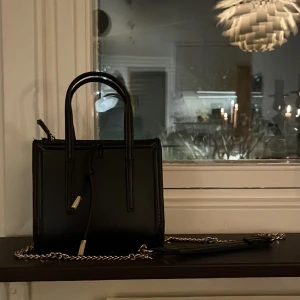 Zara väska - Svart väska med guldkedja (som går att ta bort) från zara. Köpt för ungefär 2 år sen. Använd men inga skador. Höjd upp till handtag: 27 cm, bredd: 18,5 cm, djup: ca 10 cm.