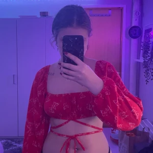 Söt croptop - Säljer min röda långärmade croptop med vita fjärils tryck på hela och snören runt magen/höften