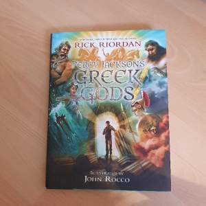 Boken Percy Jackson's Greek Gods skriven av Rick Riordan och illustrerad av John Rocco! I nyskick inbunden med dustjacket.