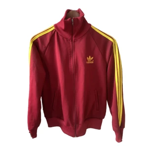 Adidas originals trackjacket  - Sjukt ball trackjacket i vinröd med gula ränder!! Köpte den i Paris för 650kr. Jag är vanligtvis en S/M och den passar som en lite oversized jacka. Hör av dig🔥🦺 (Inget adidas märke på ryggen)