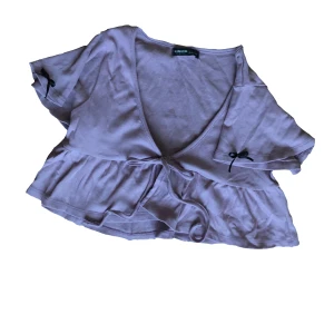 Söt lila topp med rosetter - Söt croppad topp i lila. Det står medium men jag skulle nog säga S/M. 