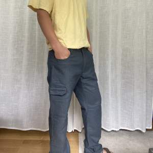Coola cargo jeans med lite kostym känsla! Innerben 87cm. Midja mätt rakt över 46cm, ben öppning mätt rakt över 22 cm   Modell: 183cm 