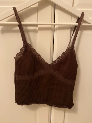 Linne från HM - Ett jätte gulligt mörkbrunt linne från HM som inte kommer till andvändning längre. Det är jätte gulligt med spets och ribbat. 