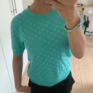 Stickad T-shirt  - Säljer denna fina stickade T-shirten i en cool turkos färg. Den är i stolek XS och köpt i en affär i Spanien för ca 320 kronor. Använd kanske Max 3 gånger men har nu hängt orörd i garderoben i över 1 år.
