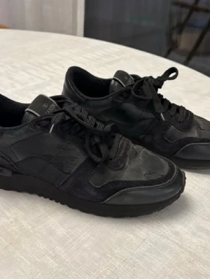 Svarta sneakers från Axel Arigato - Säljer ett par svarta Valentino Rockrunner i läder. Skorna är i bra använt skick, cirka 8/10, med normala tecken på användning men fortfarande mycket kvar att ge. Hör av er vi fundering eller frågor svarar snabbt😊