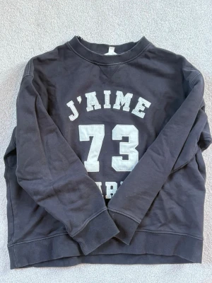 Svart sweatshirt J'AIME 73 PARIS - Cool svart sweatshirt med trycket 'J'AIME 73 PARIS' i vitt framtill. Tröjan har rund halsringning och är i storlek L. 💙
