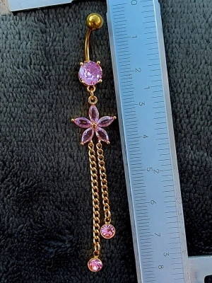 NY oanvänd Navelpiercing med långt hänge | Kirurgiskt stål | Blomma, kedjor och rosa stenar  - 💕30% Bundle-rabatt vid köp av minst 2 artiklar. ⭐️NY oanvänd piercing i kirurgiskt stål; rostfritt och säkert för läkta piercingar.                               📏MÅTT ⭕️Stavens längd: 10mm ⭕️Stavens tjocklek: 1,6mm ⭕️Smyckets totala längd: 80mm                                                                         🤍Färger: Guld och rosa                                                            💌Skickas spårbart via Plick SafePay.