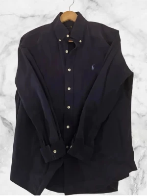 Ralph Lauren Skjorta - Marinblå skjorta från Ralph Lauren. Inga deffekter och mycket bra skick. Storlek M. Priset är ej slaget i sten ! Skriv gärna om du har frågor eller vill ha detaljerade bilder.