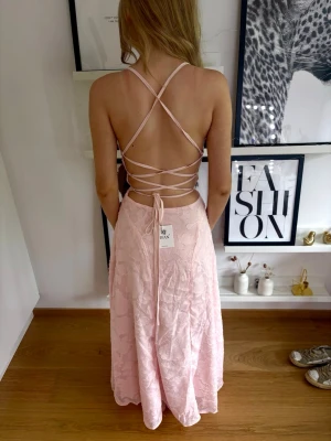 Ljusrosa balklänning 🤍🩷 - Säljer en aldrig använd ljusrosa långklänning med öppen rygg och snygg snörning i ryggen, knyts som en korsett. Säljer då den inte riktigt passade mig när jag fick hem den efter jag köpte den online! Klänningen har tunna axelband som korsas och knyts baktill. Materialet har en lätt struktur. Perfekt till bal eller bara till sommaren!!!