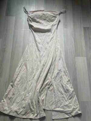 Långklänning Med Slits - Jättefin beige/vit långklänning perfekt för chill sommarkvällar eller festligheter! Köpt utomlands, endast använd fåtal gånger. 