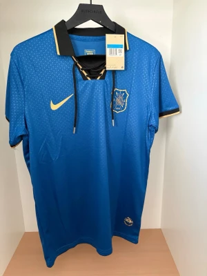 AIK Special Edition Tröja #10 - Säljer en AIK Special Edition-tröja med nummer 10 på ryggen. Tröjan har en unik blå design med gulddetaljer, klassisk snörad krage och AIK:s klubbmärke på bröstet. En ovanligare modell som sticker ut från de vanliga matchtröjorna.