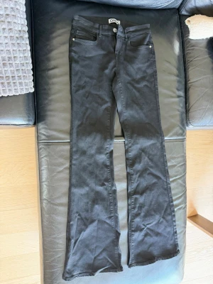 Svarta bootcut jeans från ONLY - Snygga svarta bootcut jeans från ONLY med klassisk femficksmodell och utsvängda ben. Jeansen har knapp- och dragkedjestängning samt bälteshällor. Materialet är stretchigt för extra komfort och passform.