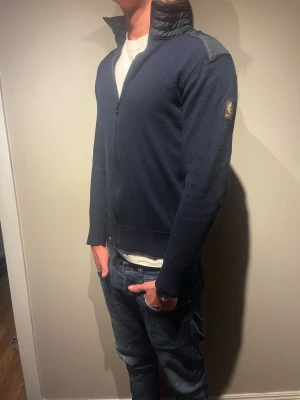 Mörklblå Belstaff cardigan - Cardigan/hybridjacka Storleken är M men tröjan har krympt till XS. Modellen är 177cm och väger 65kg. Nypris :- 3000kr