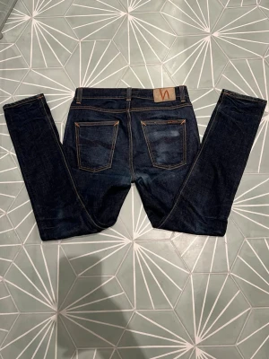 Mörkblå Nudie Jeans - Ett par sjukt stilrena mörkblå jeans från Nudie Jeans med en snygg tvätt. Modell: Lean Dean. Storlek: W31/L30. De har två små hål i framfickan som enkelt går att sy ihop, men utöver det har jeansen inga defekter. Skriv gärna vid minsta fundering🙌