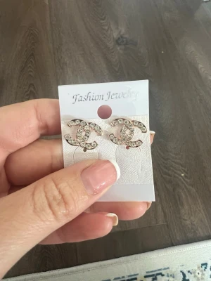 Glittriga örhängen med stenar - Snygga oanvända örhängen i form av två C:n, dekorerade med gnistrande stenar. De är silvriga och har en klassisk och trendig look som passar perfekt till att lyfta din outfit. 