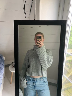 Grå ribbstickad croppad polotröja - Säljer grå ribatickad polotröja. Tröjan är kort i midjan och i storlek XS. Dock väldigt oversized. Använd men i väldigt fint skick, inga tydliga tecken på användning.