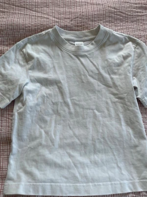 Vit basic t-shirt i bomull - En enkel vit t-shirt med rund hals och korta ärmar. Tillverkad i mjuk bomull, perfekt för en clean och avslappnad stil. Passar till allt och är ett måste i garderoben. T-shirten är ifrån Gina tricot och är i storleken xxs. 
