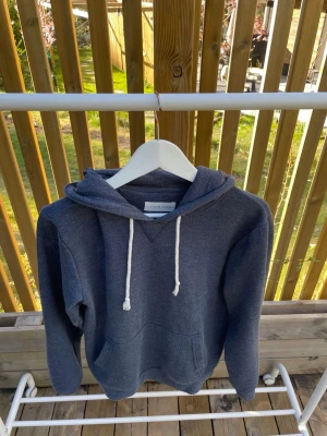 Blå hoodie med vita snören - Blå hoodie från pier one med klassisk känguruficka och vita dragsnören i huvan.