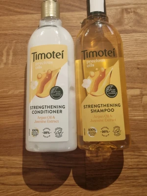 Timotei Precious Oils schampo & balsam - Säljer ett set med Timotei Precious Oils Strengthening Shampoo och Conditioner, båda med arganolja och jasminextrakt. Flaskorna är 300 ml vardera, schampot är gyllene och balsamet vitt. Perfekt för dig som vill ha naturlig hårvård med växtbaserade ingredienser.