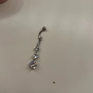 Silver navelpiercing med glittriga stenar💕 - Elegant navelpiercing i silverfärg med flera glittriga stenar i olika storlekar. Aldrig använd! Längd=10mm hänge=45mm⚠️