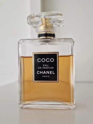 Coco Eau de Parfum från Chanel - Original Coco Eau de Parfum, 100 ml från början. Parfymen är använd, cirka 70% kvar (se bild för exakt nivå). Köpt för flera år sedan(7 år). När det gäller parfymen är koden 3301, den syns bara inte så tydligt på bilden. Eftersom den är cirka 7–8 år gammal kan det hända att doften har förändrats lite eller att hållbarheten inte är densamma som när den var ny.Locket kan sitta på parfymen, men mekanismen som håller fast det fungerar inte, men det påverkar inte parfymens funktion. Ingen originalkar