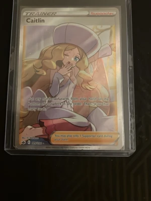 Pokémonkort Caitlin Trainer Full Art - Säljer ett Pokémonkort av typen Trainer Supporter med motiv av Caitlin. Kortet är en Full Art-variant med holografisk yta och ligger i ett skyddande plastfodral. Perfekt för samlare eller Pokémonfans som vill utöka sin samling.