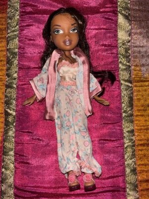Vintage Bratz docka Y2K med original pyjamas/kimono-outfit - Vintage original Bratz-docka från tidigt 2000-tal i mycket fint skick. Dockan kommer med sitt original pyjamas/kimono-set och matchande skor. Långt mörkt hår, fint ansikte och snygg makeup utan synliga skador. Alla delar som syns på bilderna ingår.  Perfekt för samlare, nostalgiker eller dig som älskar Y2K och klassiska Bratz.  Skick: Mycket bra